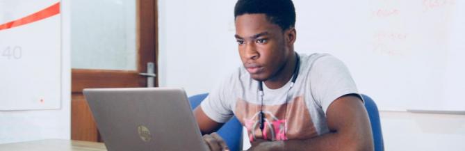 Black male student working on a laptop